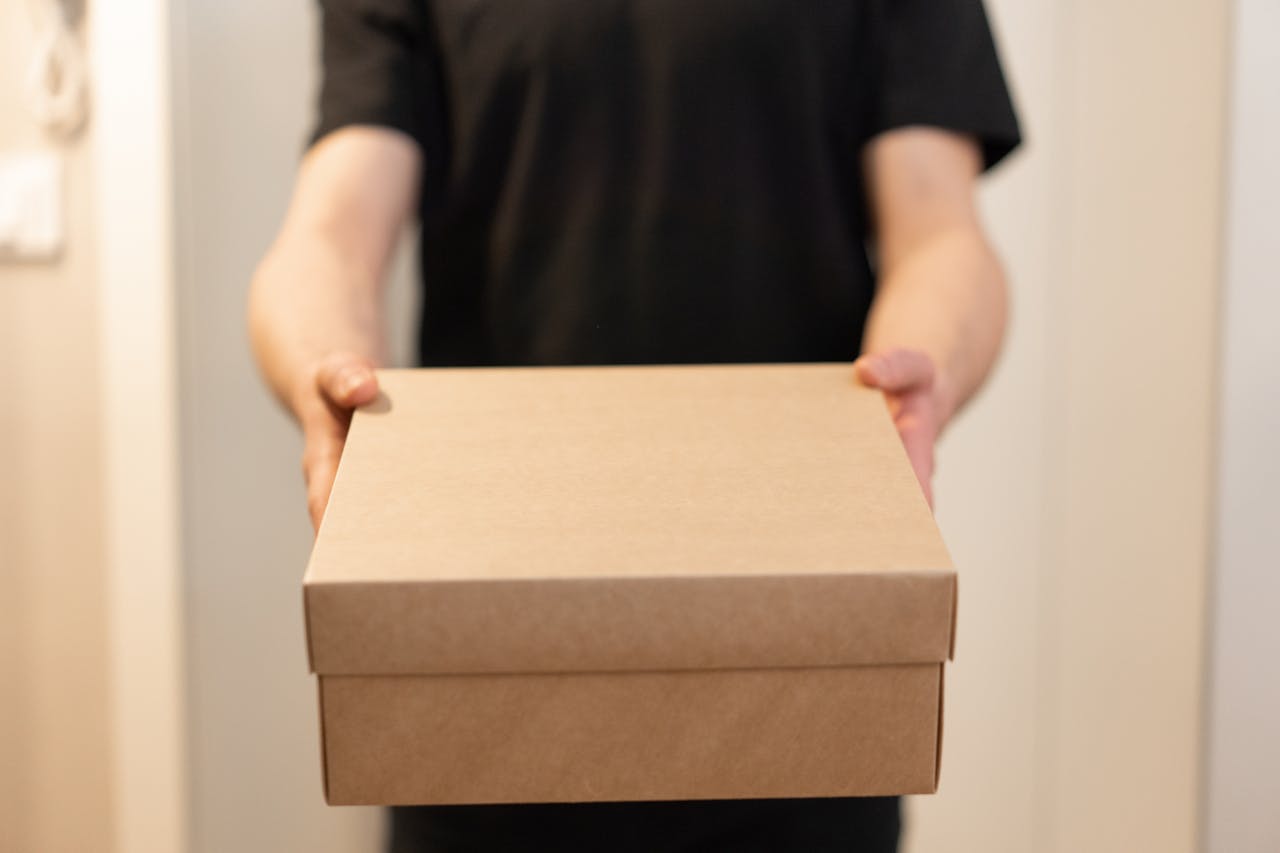 about-us Close-up of a person holding a cardboard box, ideal for delivery service concepts.